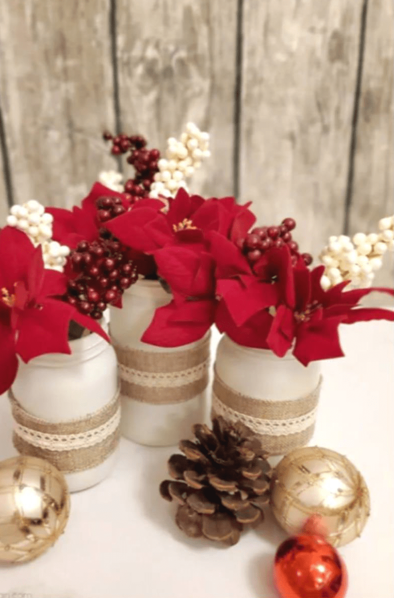 Rote Weihnachtssterne mit weißen Kerzen und Christbaumkugeln auf einer Tafel