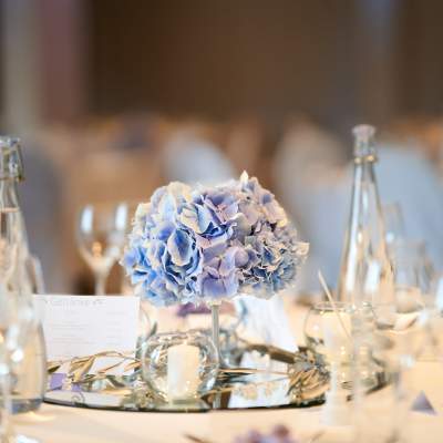 Blaue Hortensie mit Kerzen und Glasdekoration auf einer Hochzeitstafel