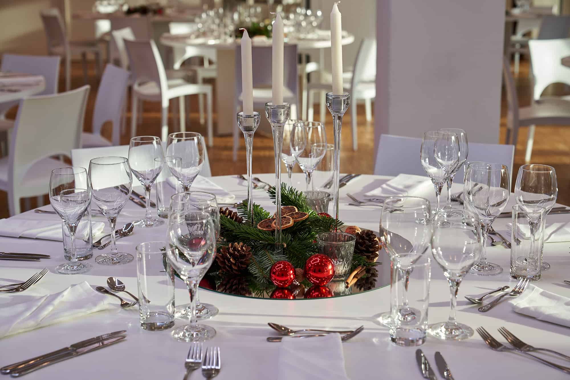 Festlich gedeckte runde Tafel mit winterlichem Tischgesteck und Kerzenleuchter