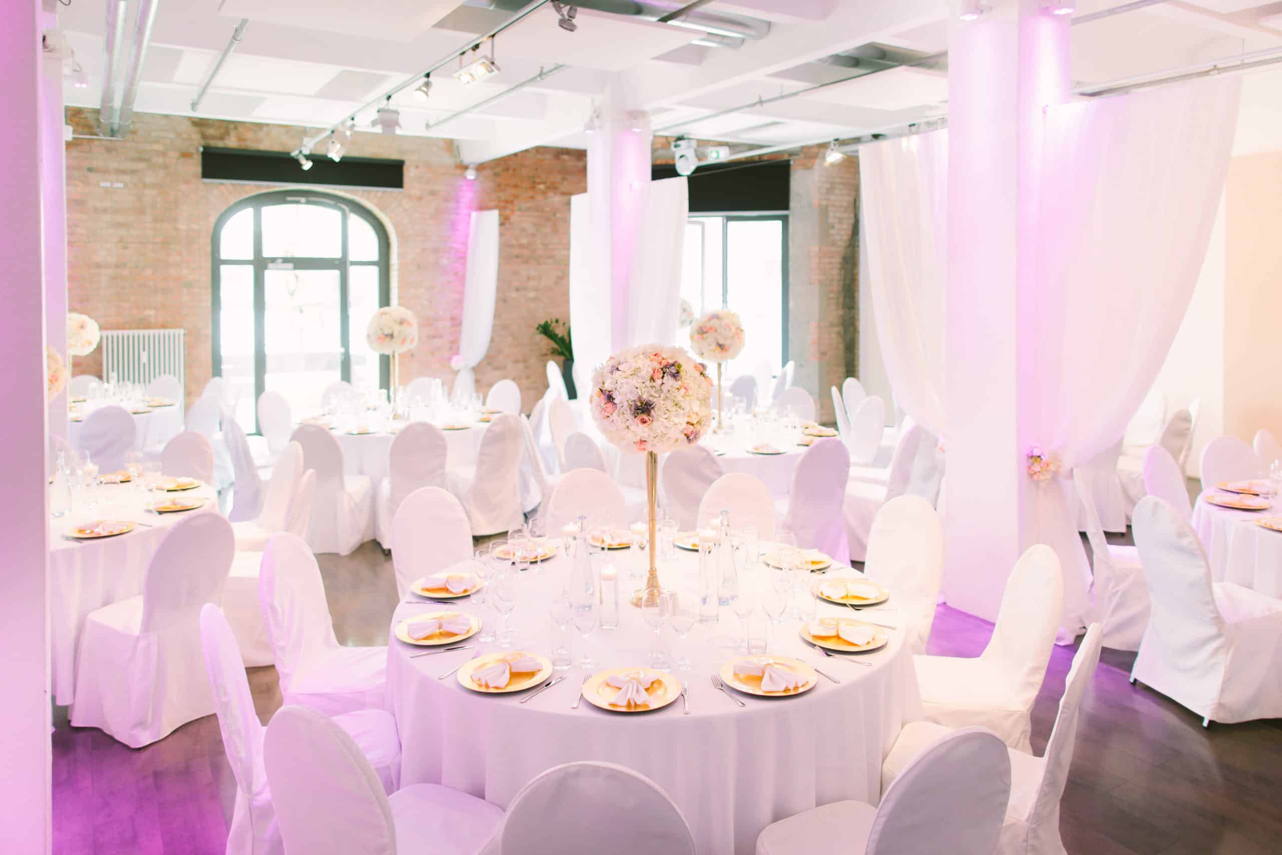 Runde Hochzeitstische mit Kerzen und weißer Tischwäsche im Loft