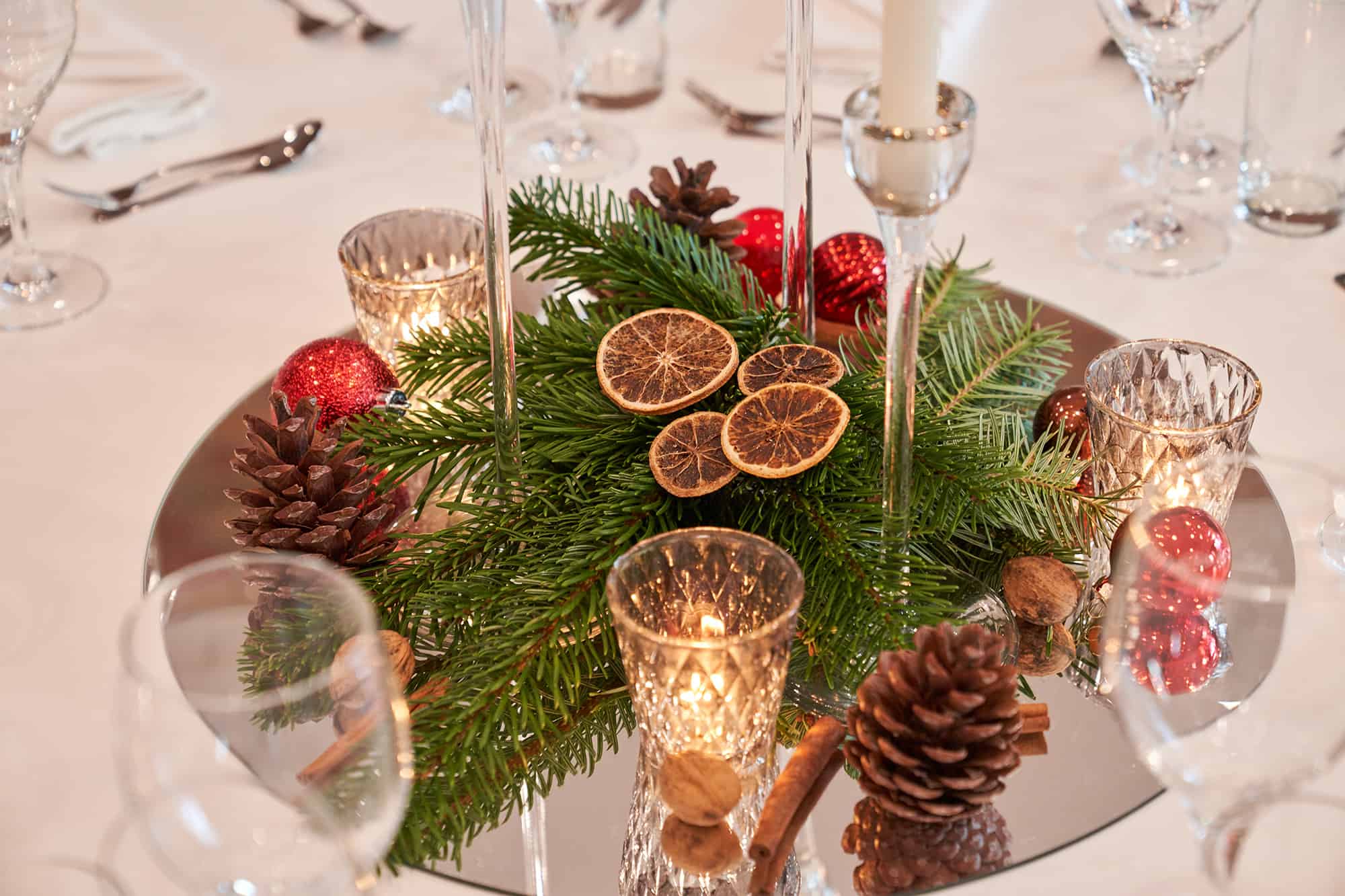 Winterliches Gesteck mit roten Rosen, Orangenscheiben und grünen Zweigen