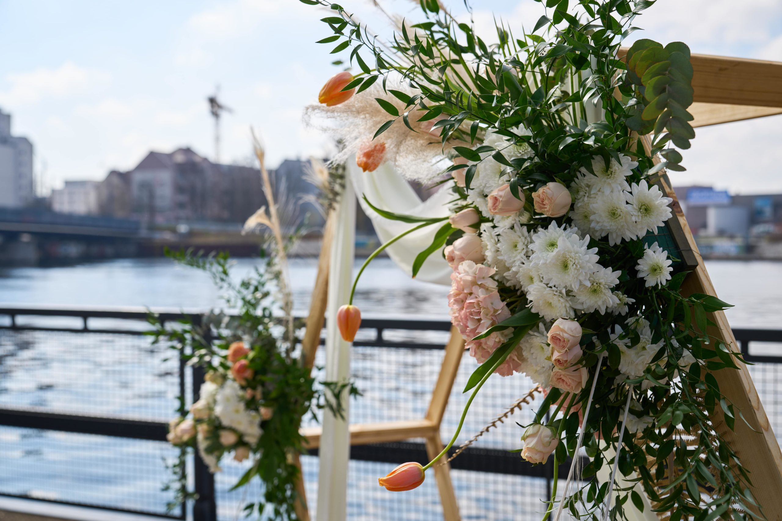 Weißes und rosafarbenes Blumengesteck am hölzernen Traubogen