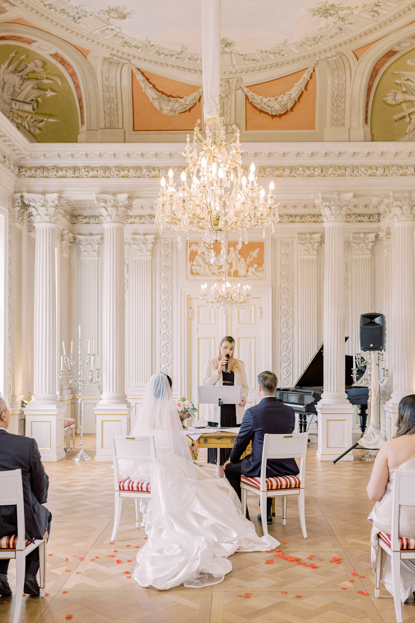 Impression von Marie Beyer: eine Hochzeitszeremonie findet in einem hellen Saal mit Kronleuchter statt