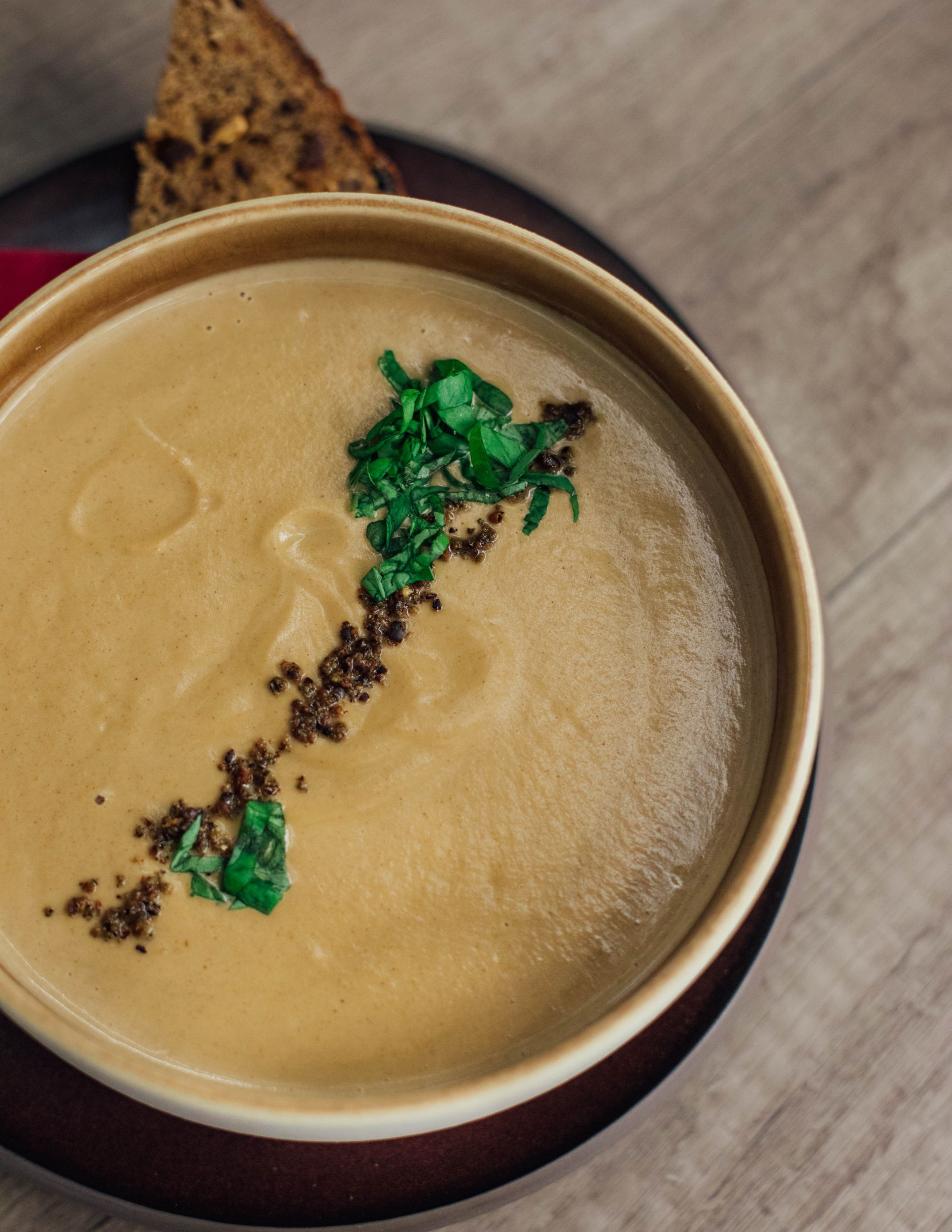 Cremige Suppe mit Kräutern und Brot in einer Schale