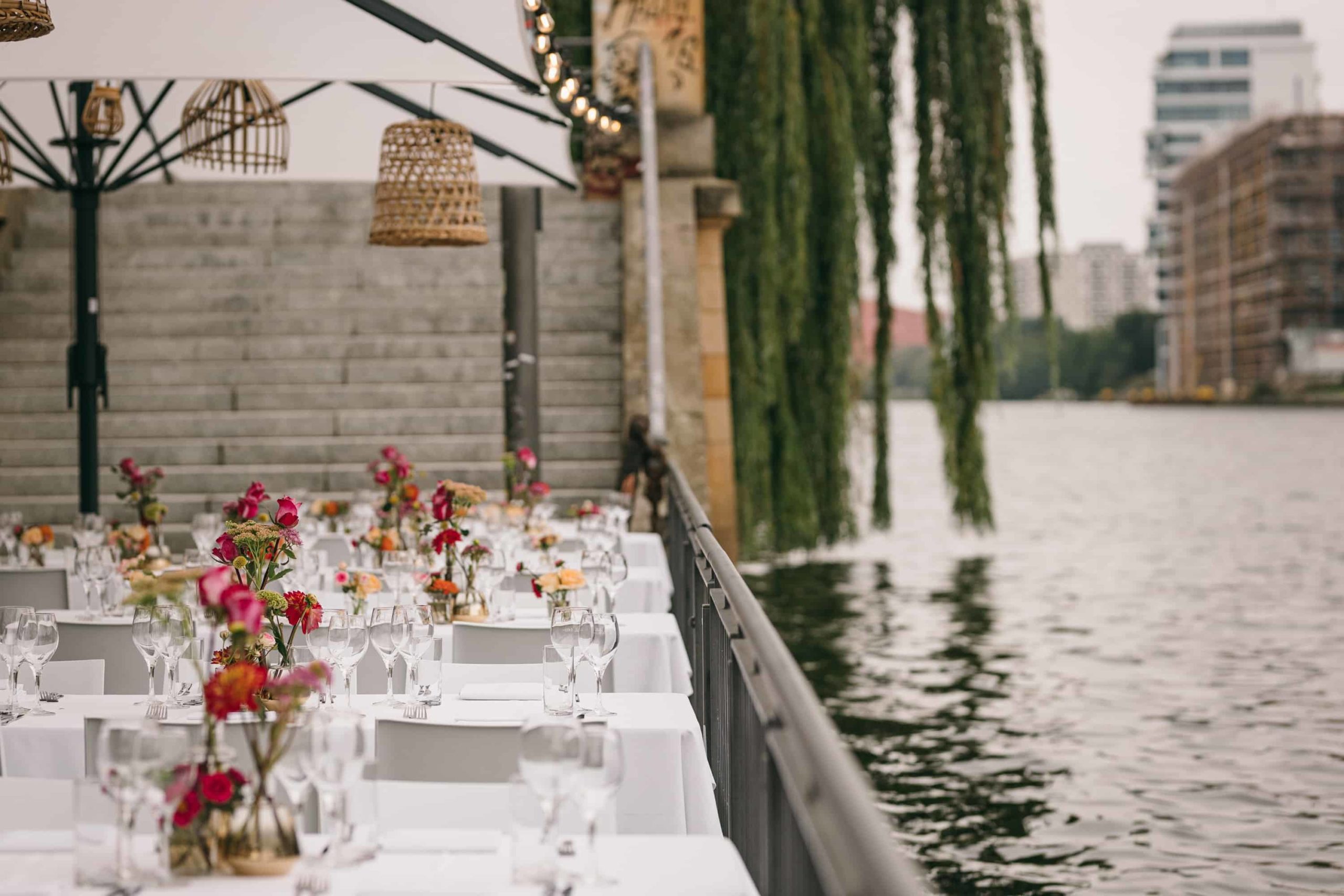 Weiße Hochzeitstafel mit Blumenschmuck direkt am Spreeufer