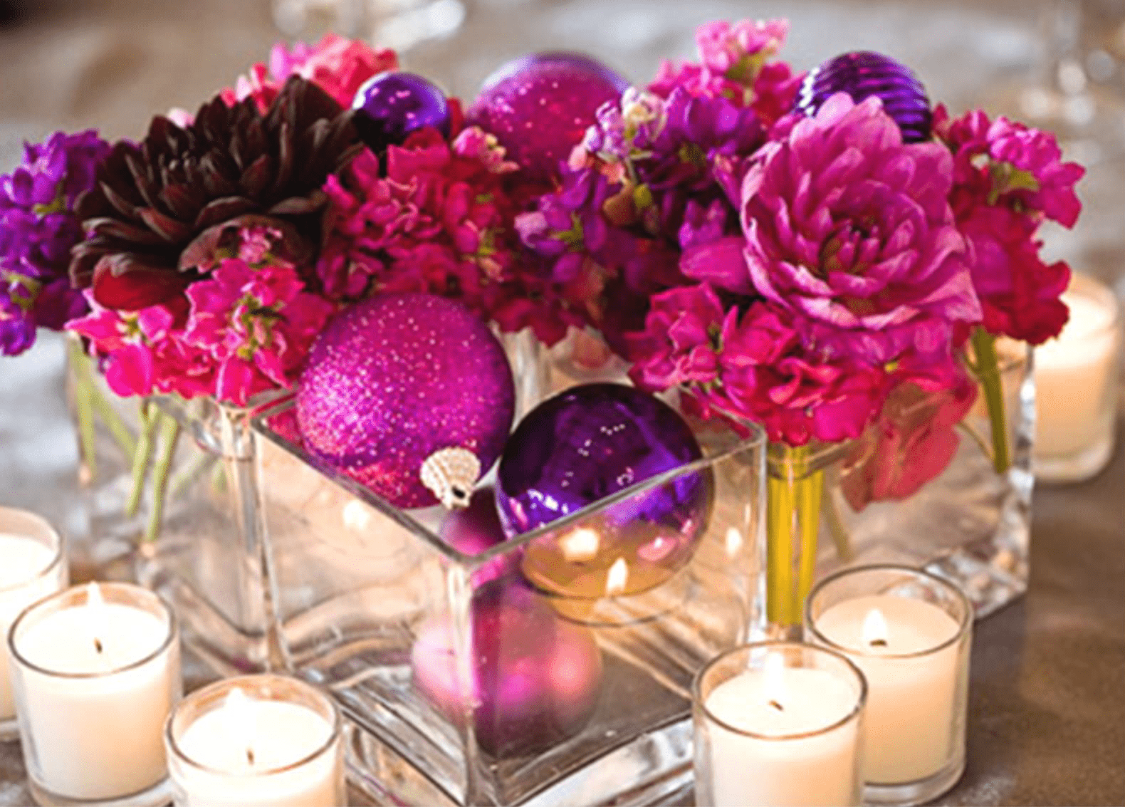 Rosa und violette Blüten mit Kerzen in goldfarbenen Glasgefäßen