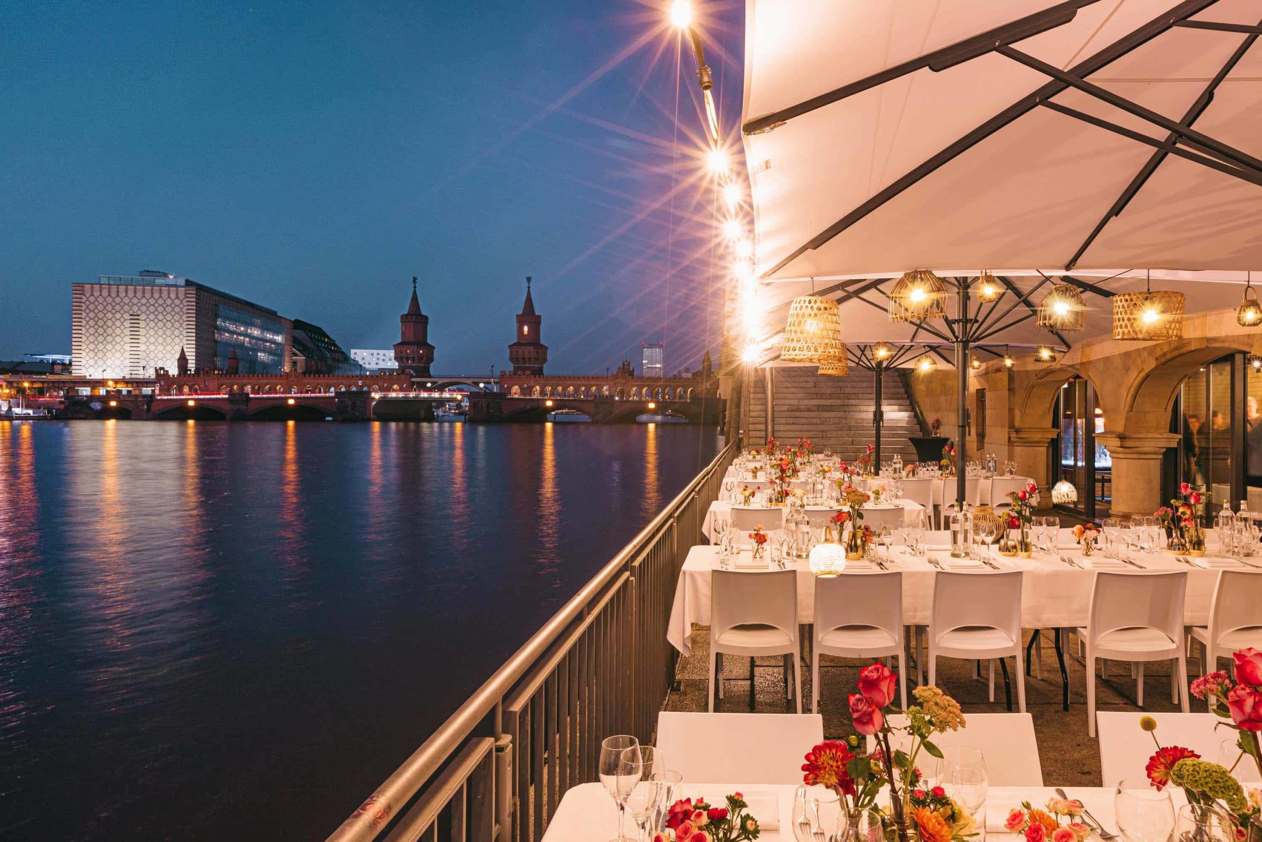 Beleuchtete Terrassentische an der Spree in der Abenddämmerung