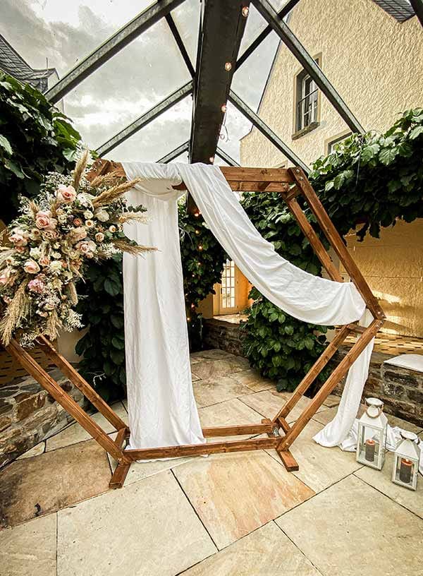 Hexagon-Traubogen mit weißem Tuch und Blumenschmuck