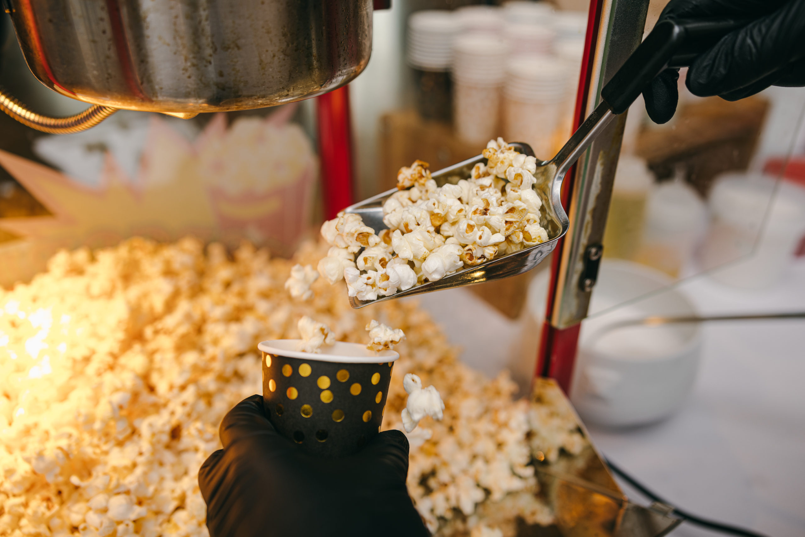 Popcorn wird mit der Schaufel in einen Becher gefüllt