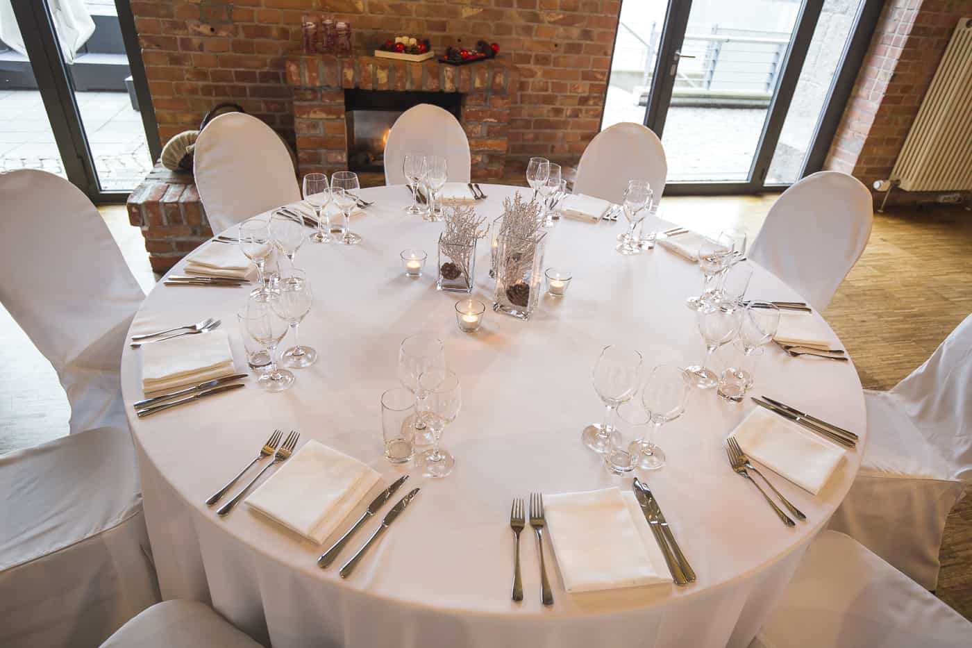 Runde weiße Festtafel mit Kerzen und winterlichen Dekorationen
