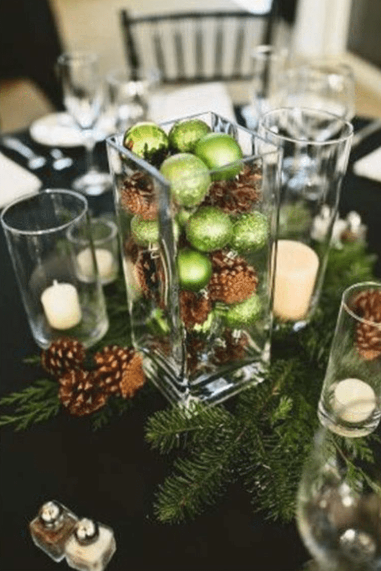 Grüne Christbaumkugeln und helle Kerzen auf einem festlich gedeckten Tisch