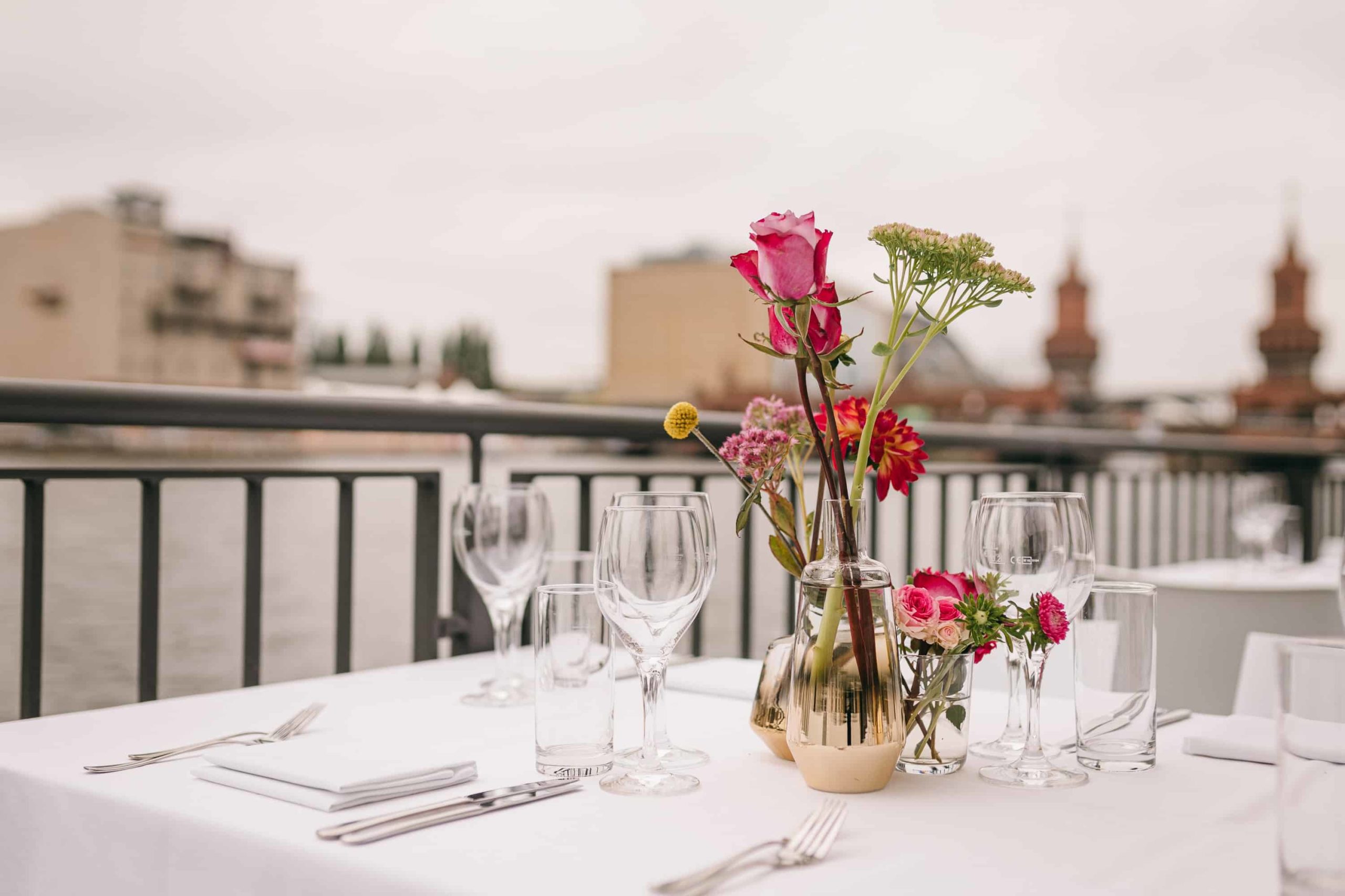 Blumendekoration und Gläser auf einem weißen Terrassentisch