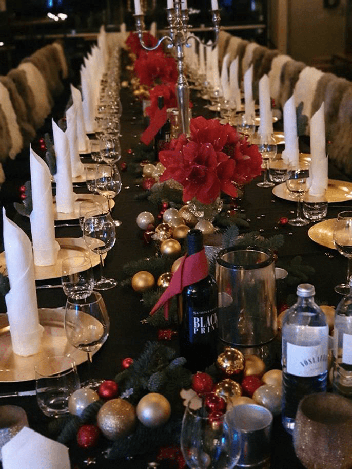 Rotes und grünes Blumengesteck mit Kerzen auf einer Festtafel