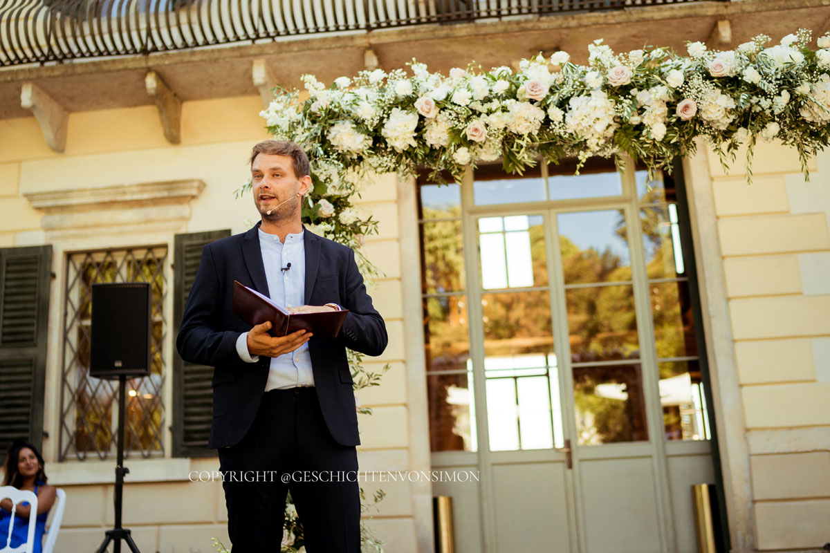 Impression von Dr. Johann-Jakob Wulf: ein Trauredner steht mit Unterlagen vor einer blumengeschmückten Hochzeitskulisse