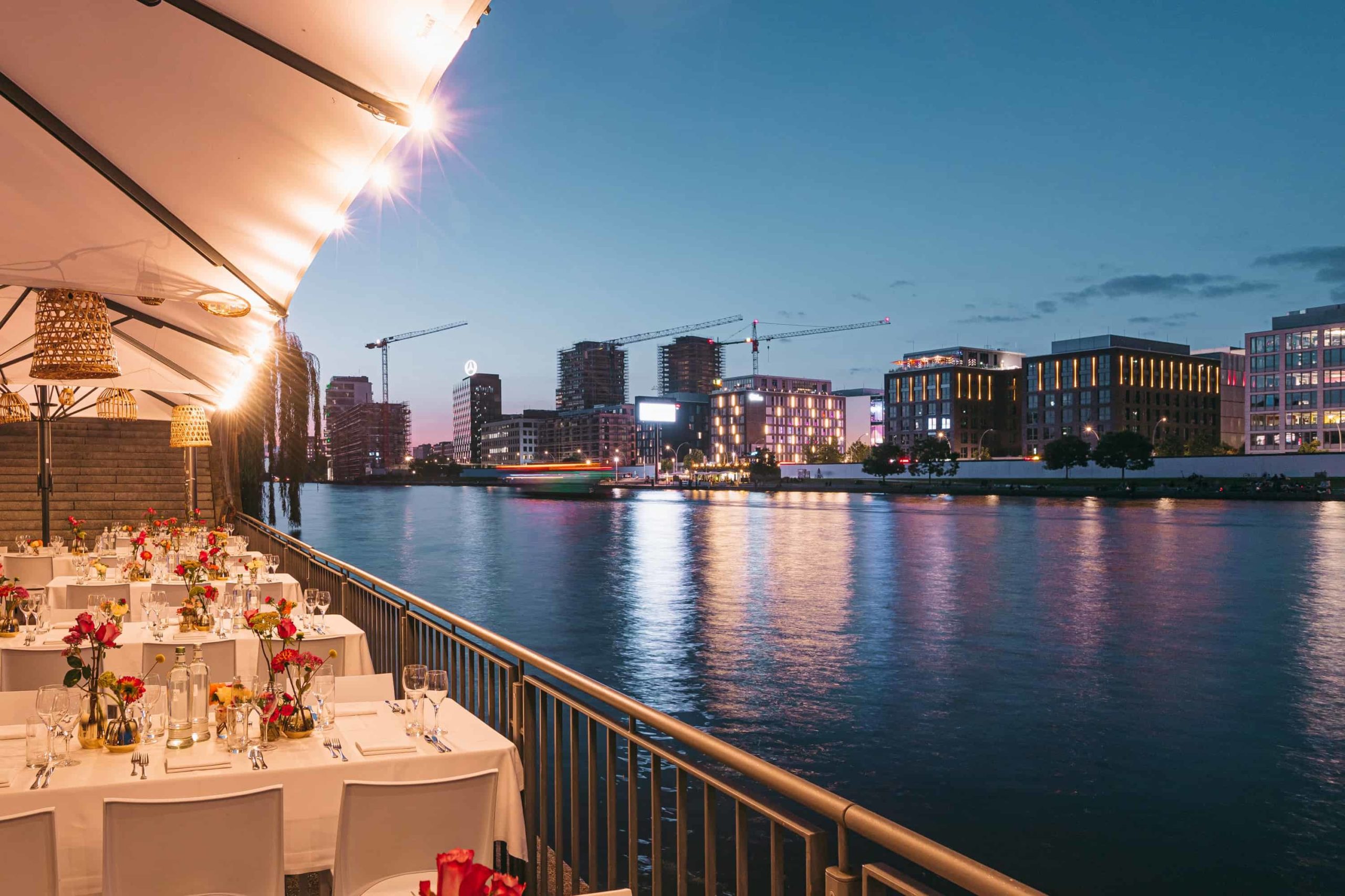 Gedeckte Terrassentafel mit Blick über die Spree am Abend