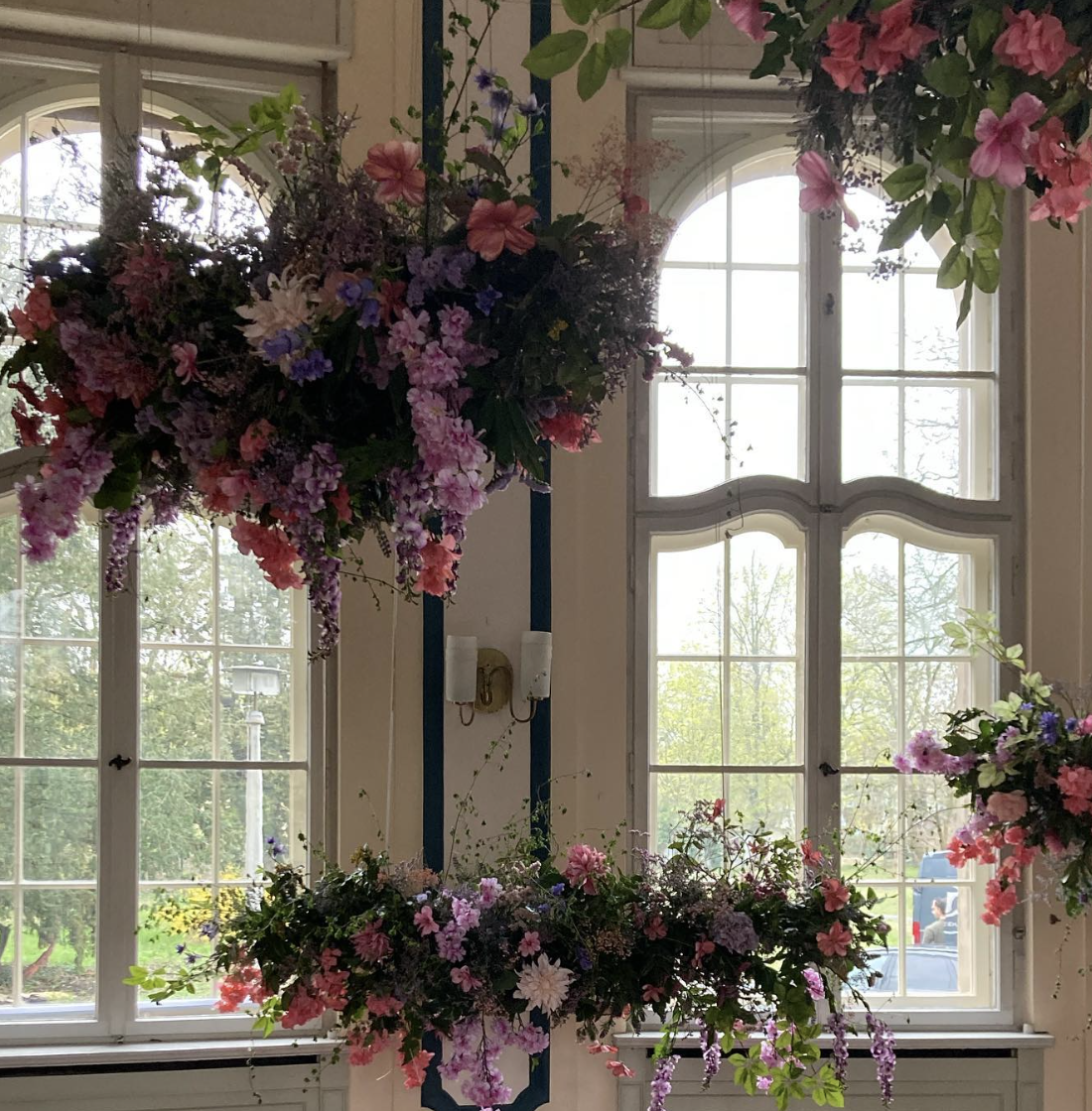 Hängende Blumeninstallation vor Sprossenfenstern