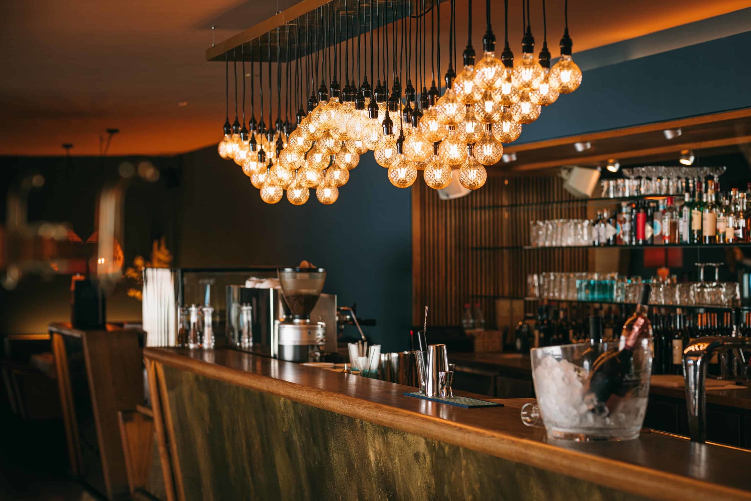 Bar mit Gläsern unter dekorativen Pendelleuchten