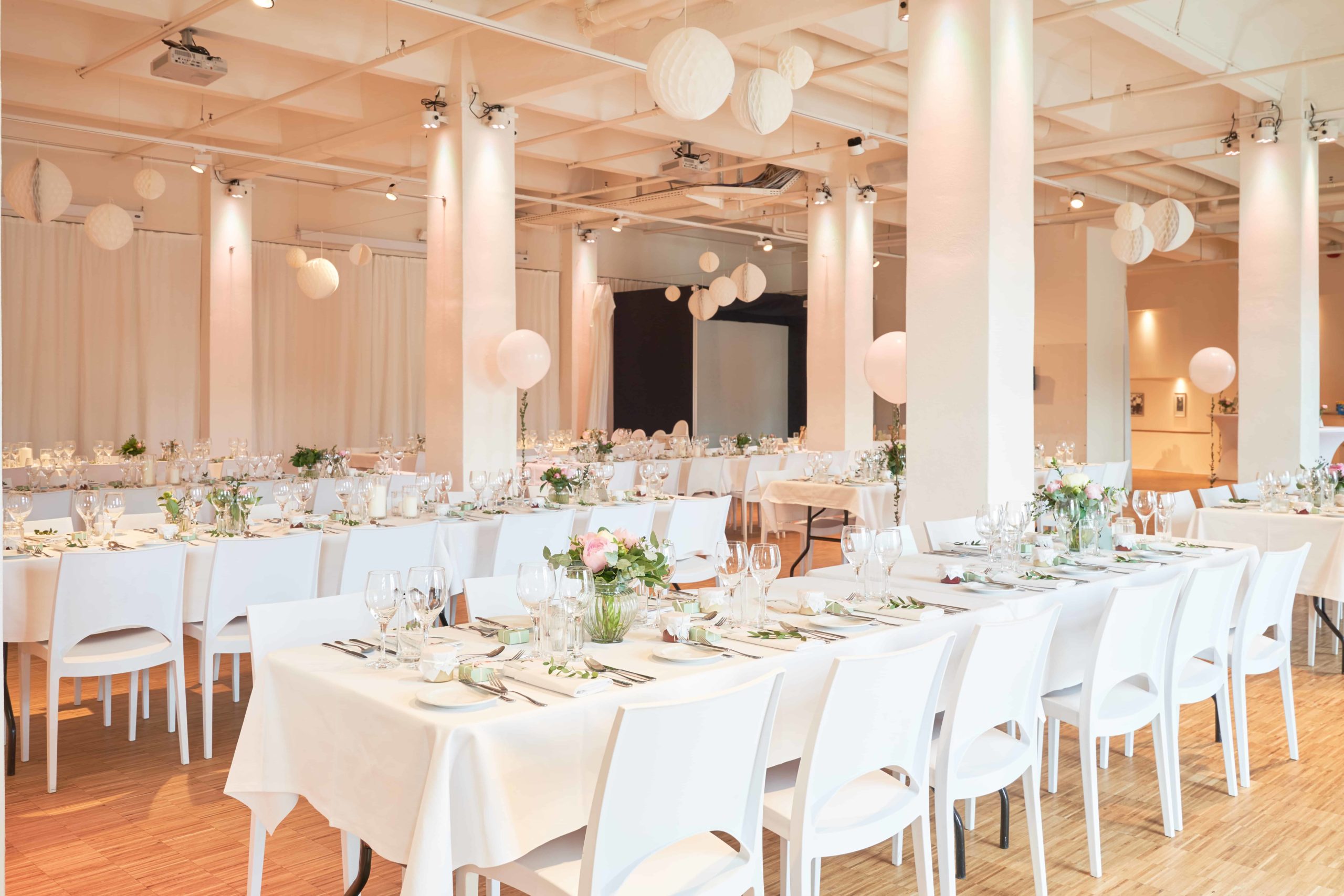 Festlich gedeckte Hochzeitstische mit weißen Stühlen und Lampions